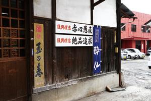 工場の壁に掲げられている会社ののぼりと復興理念「赤心愚直」「絶品追求」